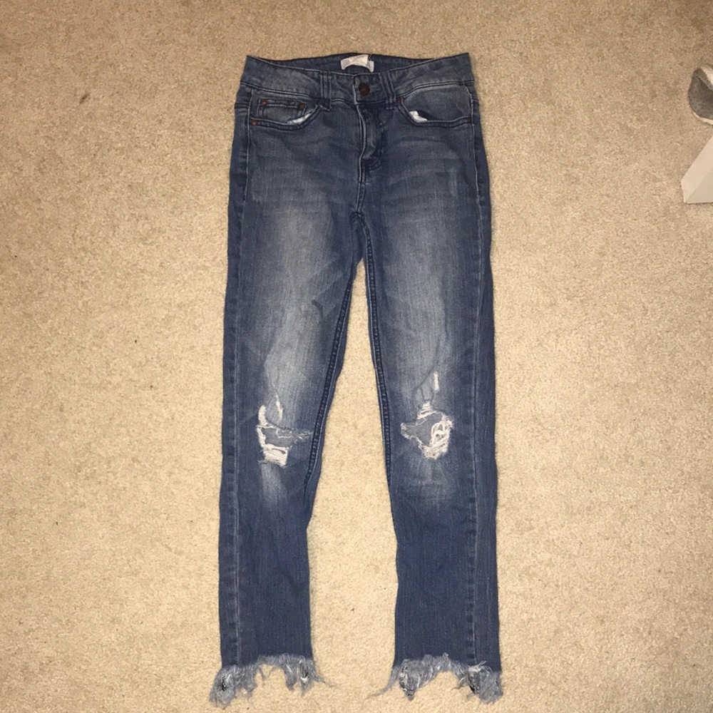 Ripped denim jeans with fringed ankles